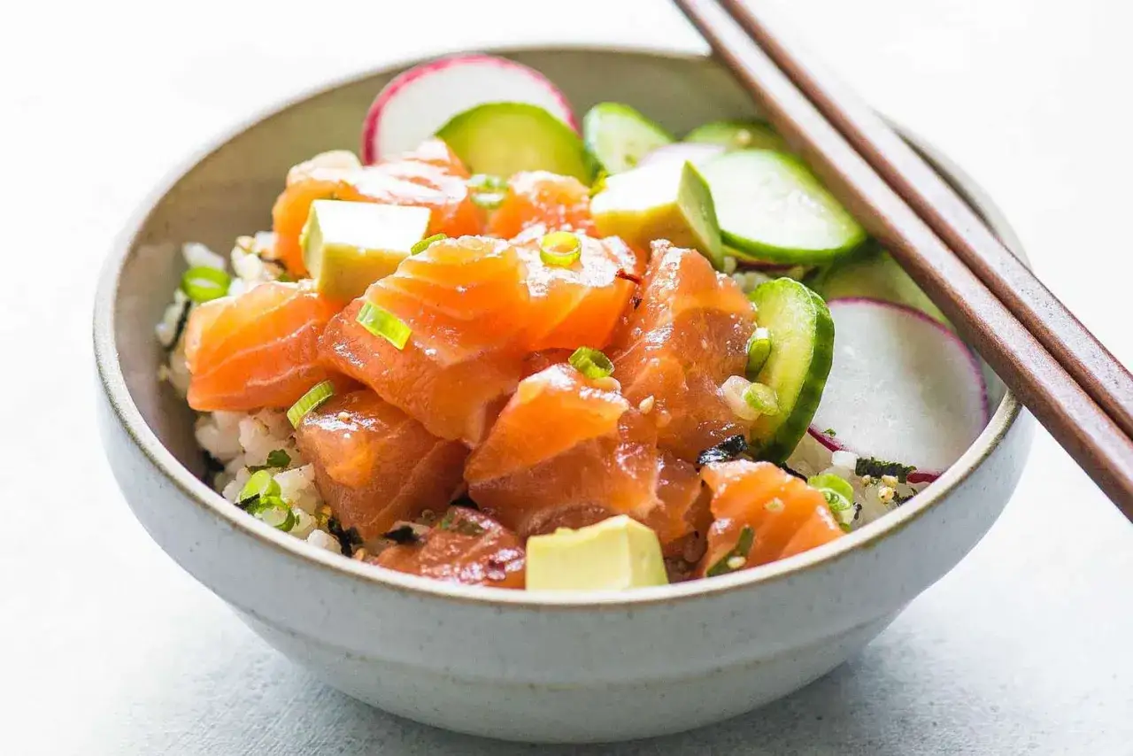 En sk&aring;l med lax poke, ris, gurka, r&auml;disa och avokado. En h&auml;lsosam och f&auml;rgglad m&aring;ltid.