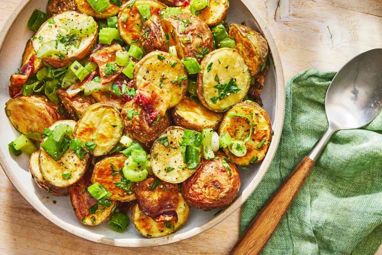 En skål med gyllene, ugnsbakad potatis, toppad med färska örter och salladslök. Perfekt tillbehör!