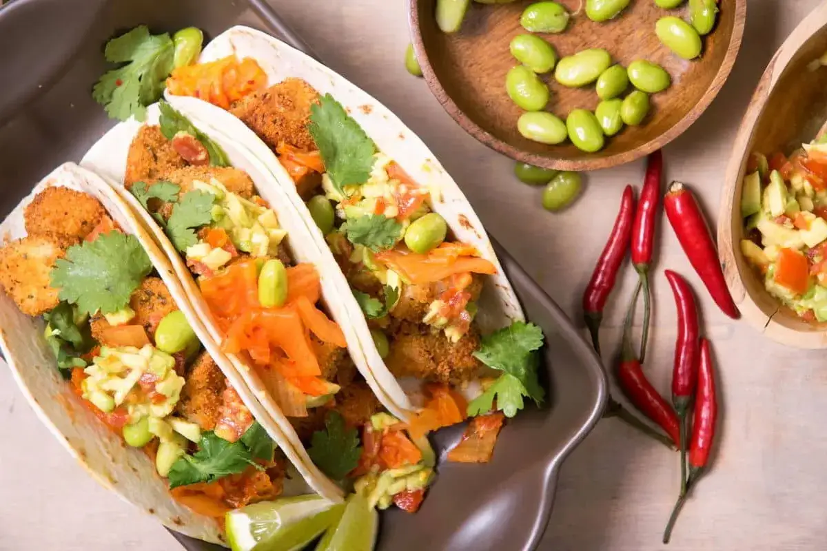 Tacos med krispig fyllning, avokado, edamame och en smakrik kimchi sås. Serveras med lime och chili.