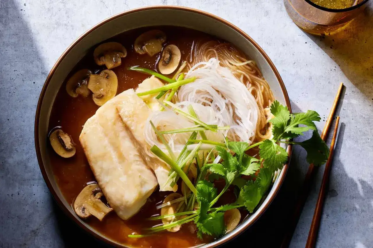 En skål med fisk, risnudlar, champinjoner och koriander. Ett enkelt fisk recept som ser utsökt ut.