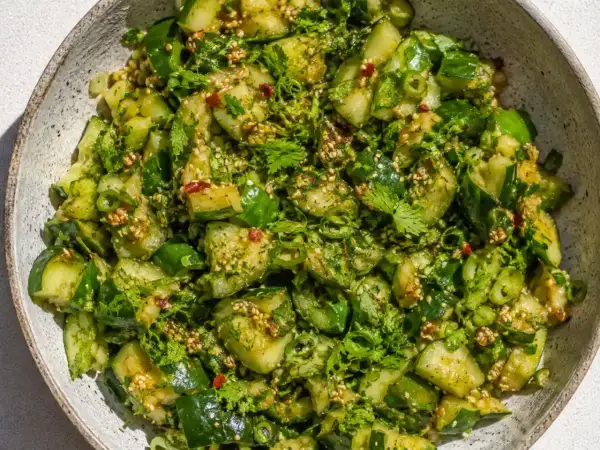 En skål med en matig sallad av gurka, örter och sesamfrön.